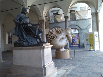 foto del loggiato di Palazzo Pretorio di Lucca con la statua del civitali ed una figura costruita in cartone
